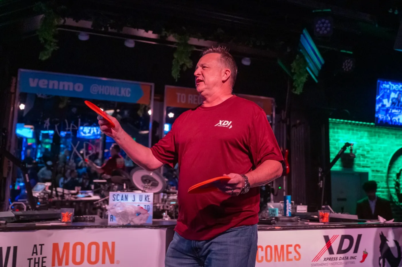 Kansas City corporate event photography - host tossing gift-card frisbees to the crowd from the stage