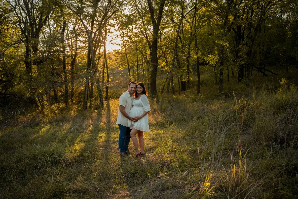 Kansas City maternity photographer - wide golden-hour photo of a couple in a forest clearing