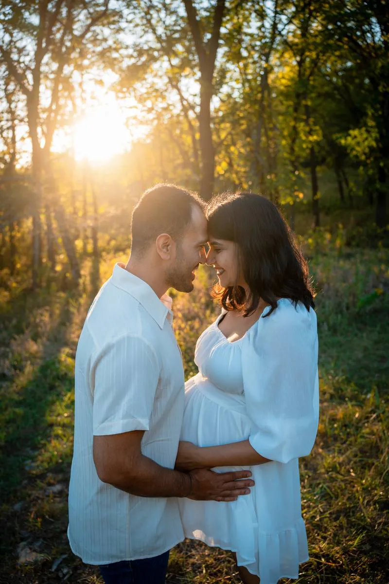 Kansas City maternity photographer - expecting couple touching foreheads in a golden-hour forest