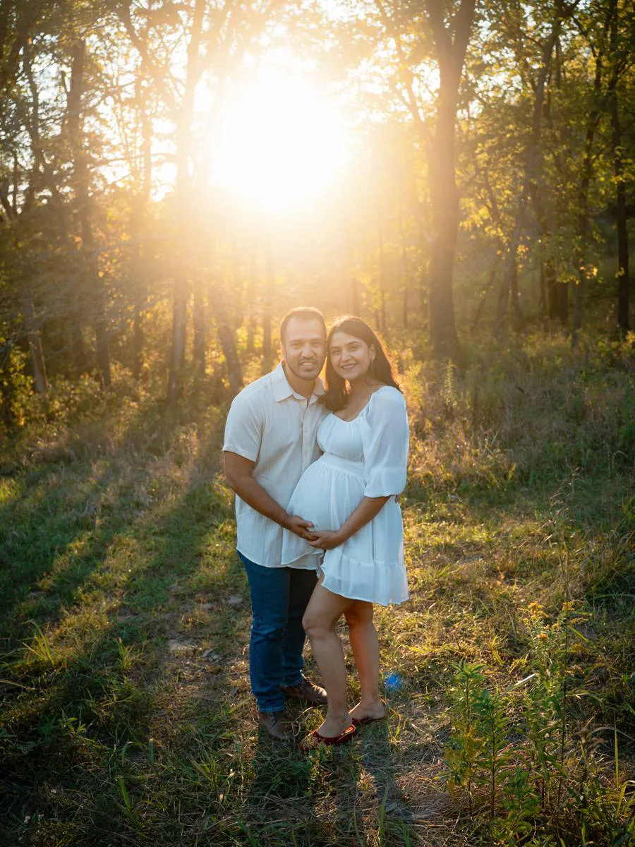 Kansas City maternity photographer - couple embracing as the sun bursts through the trees