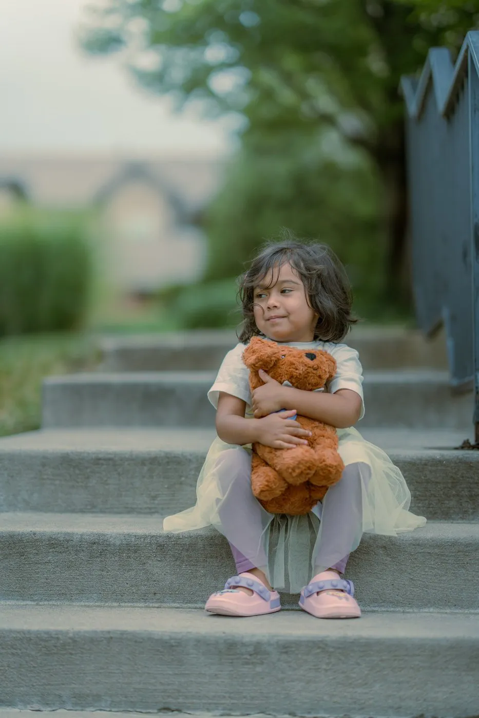 Kansas City family photographer - toddler in a tulle dress holding a teddy bear on concrete steps