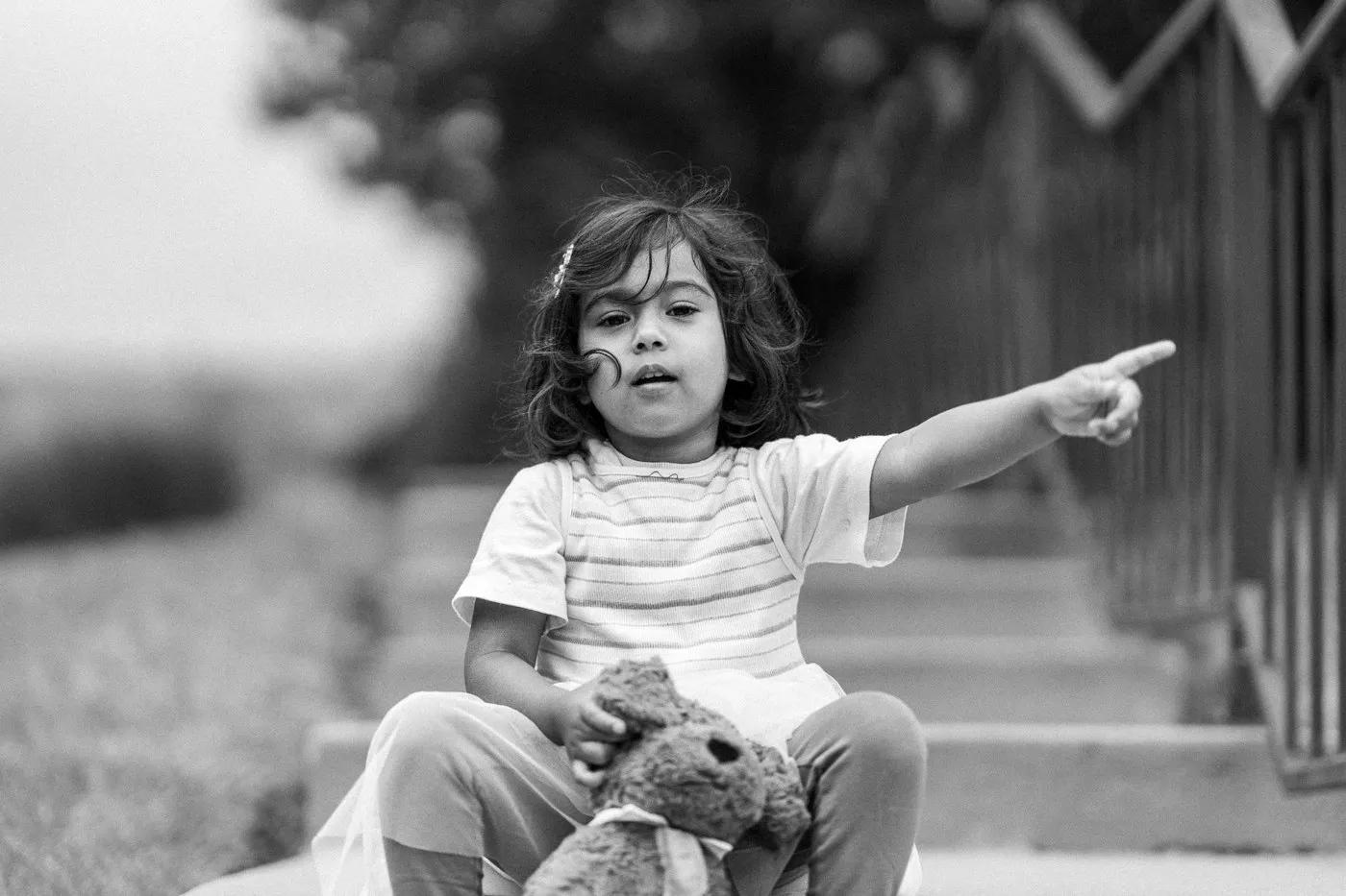 Kansas City family photographer - black and white photo of a toddler pointing, teddy bear in her lap
